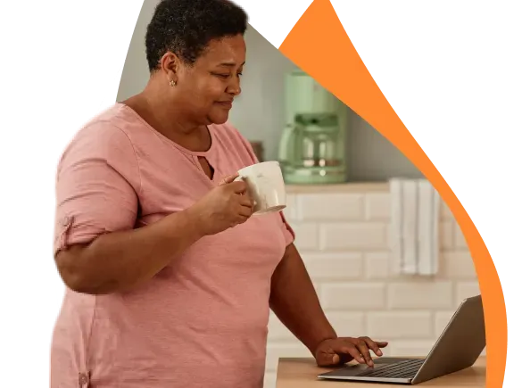 Mulher sorrindo enquanto utiliza um laptop em casa, simbolizando praticidade na busca por produtos da Copagaz.