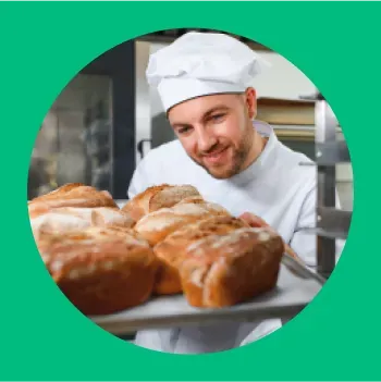 Padeiro sorridente segurando bandeja de pães frescos.
