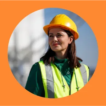 Engenheira com capacete amarelo e colete refletivo em um ambiente industrial.