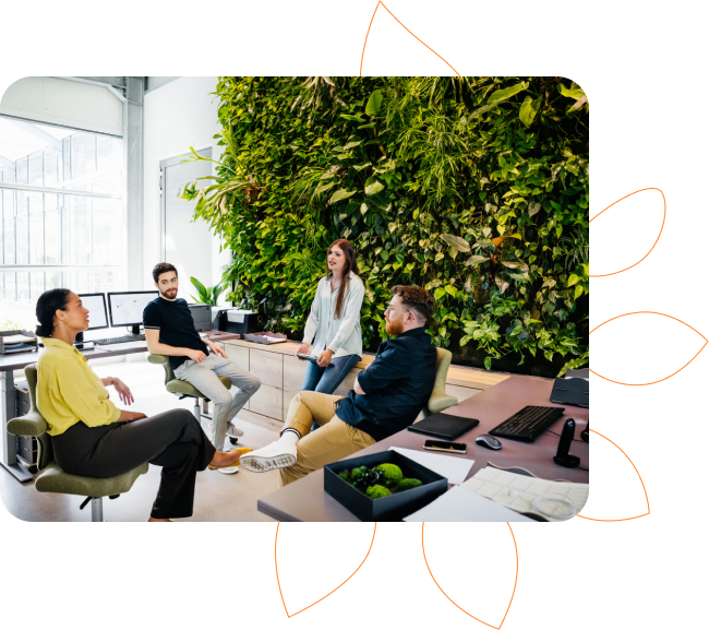 alt="Equipe reunida no escritório com parede verde com plantas"