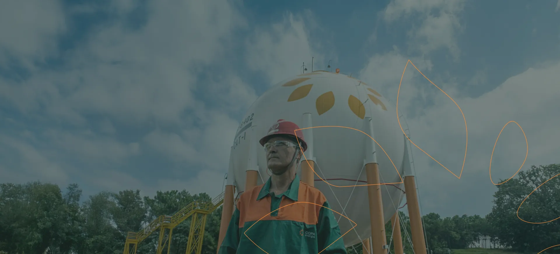 Um técnico de capacete e uniforme da Copa Energia em frente a tanques de gás