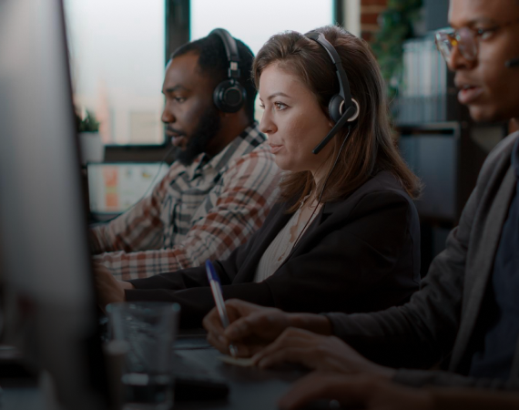 Atendentes com headset trabalhando em computadores