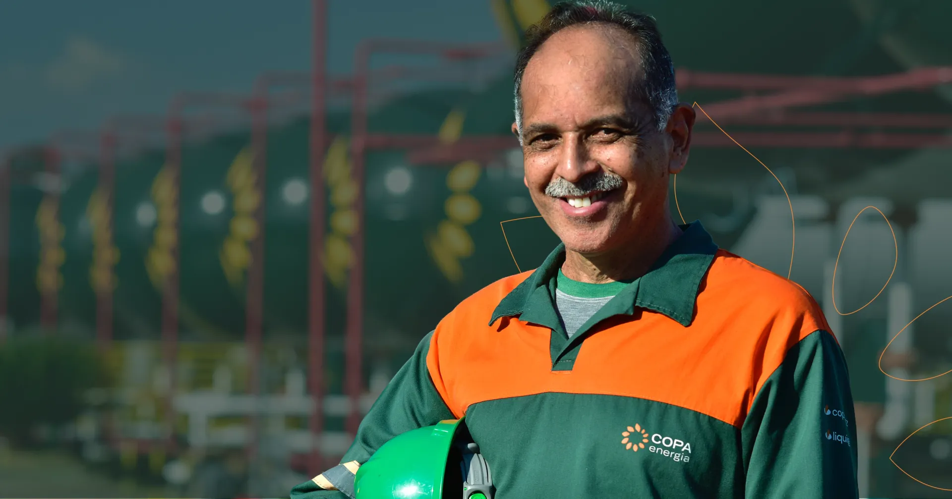 Homem sorrindo, vestindo uniforme da Copa Energia, segurando um capacete no braço