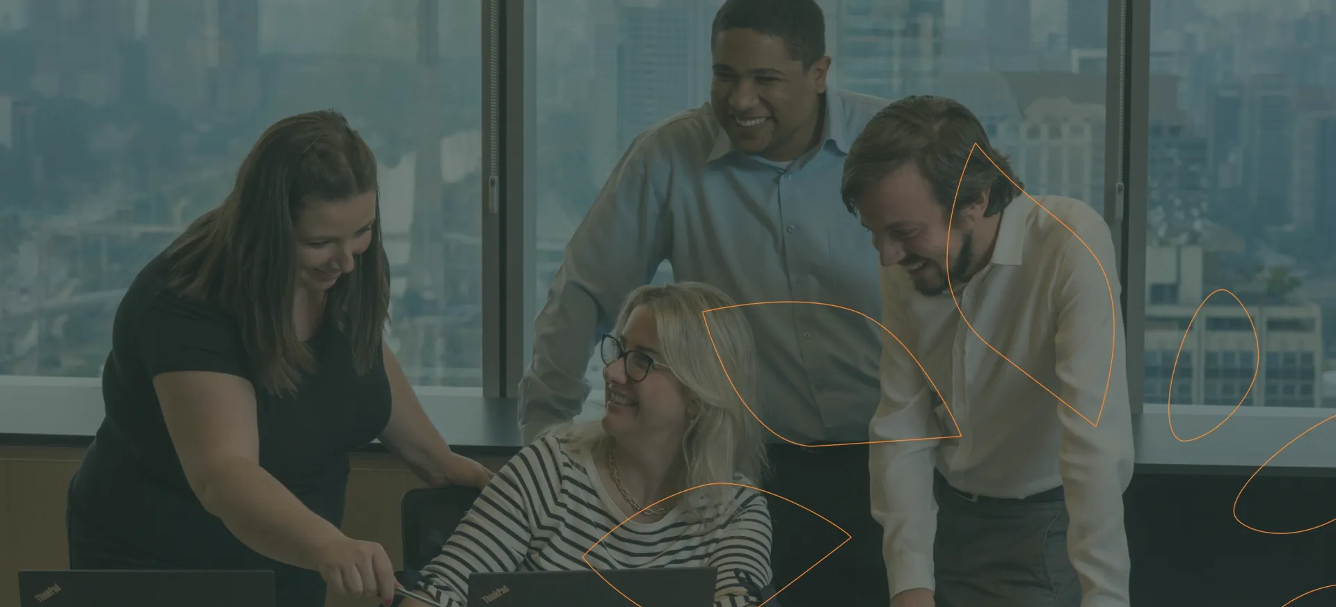 Imagem de uma equipe de quatro pessoas no escritório, olhando sorridentes para o computador